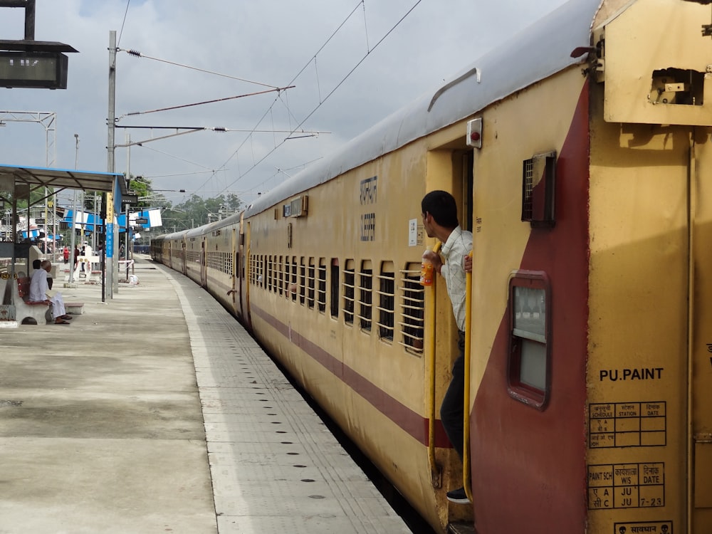 a man standing on the side of a train next to a platform