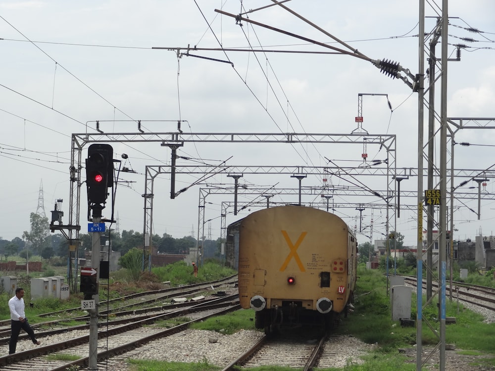 a yellow train traveling down train tracks next to a green field