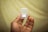 A hand holding a small clear plastic case containing a memory card. The card inside is labeled with the brand name and storage capacity details. The background is blurred and features a soft yellow tone.
