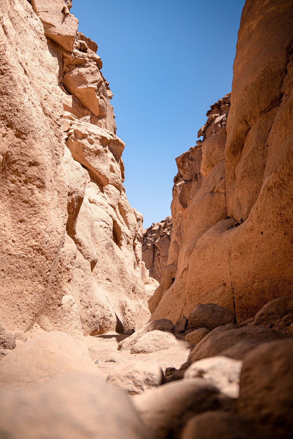 a narrow canyon with rocks and a blue sky in the background
