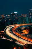 A nighttime cityscape with a vialumo car cruising smoothly along the highway.