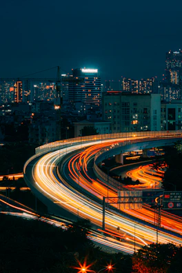 A nighttime cityscape with a vialumo car cruising smoothly along the highway.