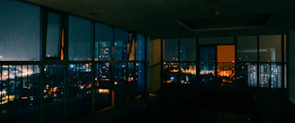 A sleek urban loft with large windows overlooking a bustling city street at dusk.