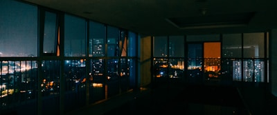 A stylish penthouse with floor-to-ceiling windows overlooking the city lights at night.