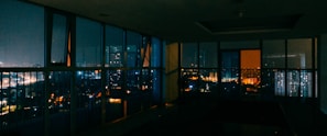 Evening cityscape viewed through a large window, with soft ambient lighting indoors