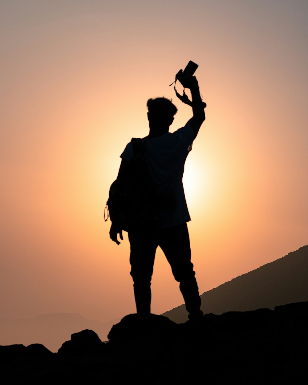 a man standing on top of a mountain holding a cell phone