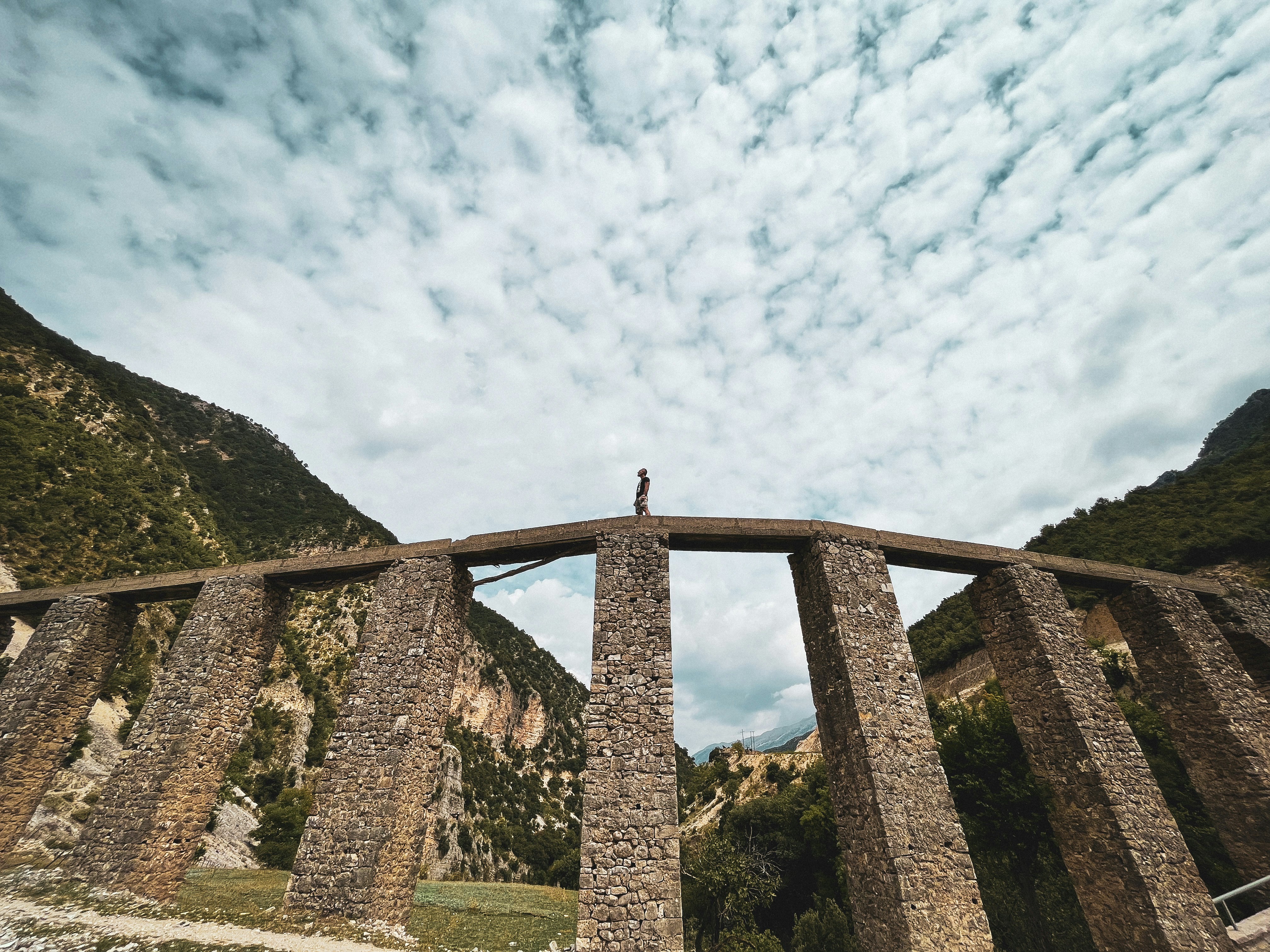 a person standing on top of a stone bridge, 