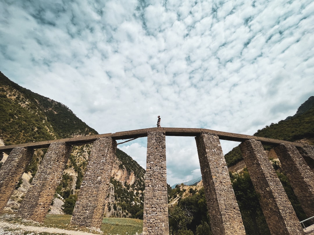 a person standing on top of a stone bridge,