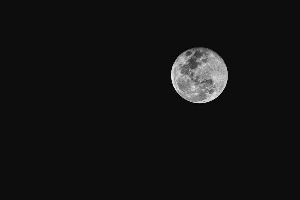 a full moon is seen in the dark sky