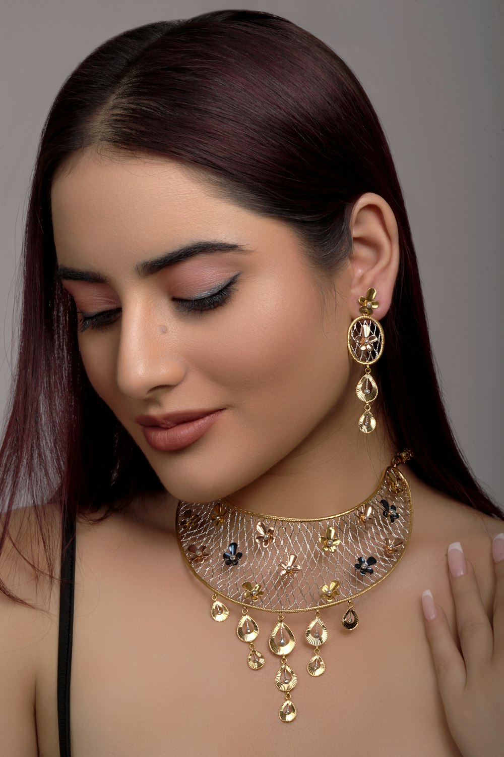 a woman wearing a gold necklace and earrings
