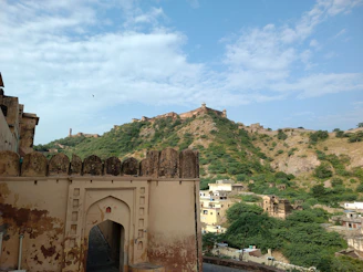 Scenic shot of Hanumant Fort standing tall amidst dense greenery and misty hills.