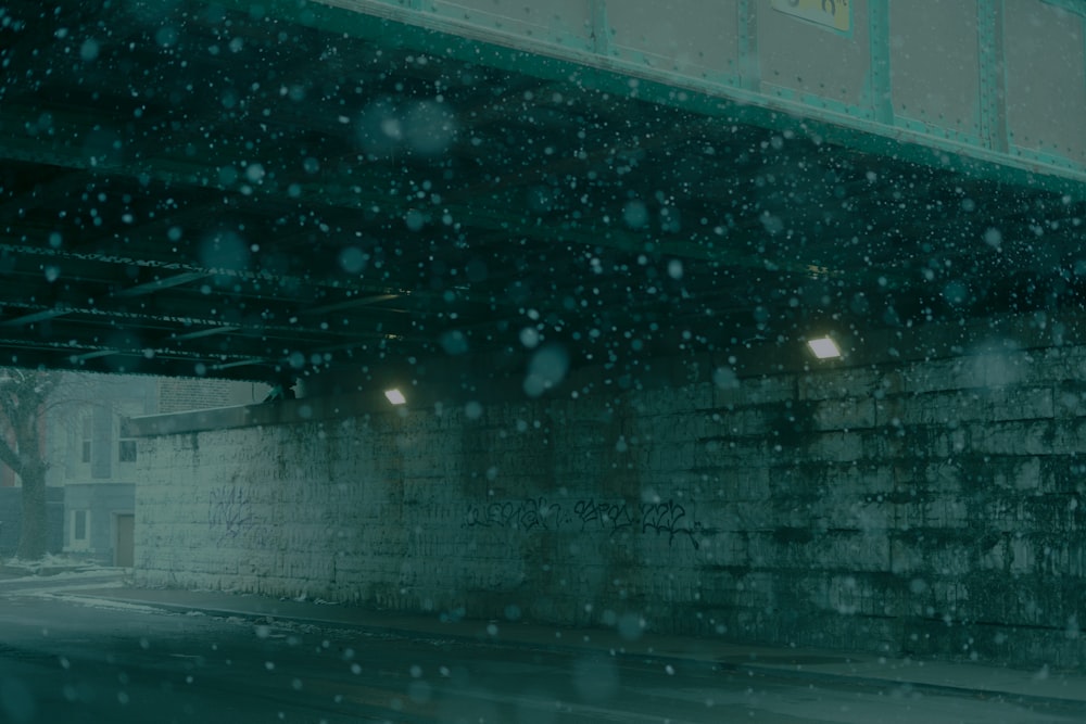 a car driving under a bridge on a snowy day