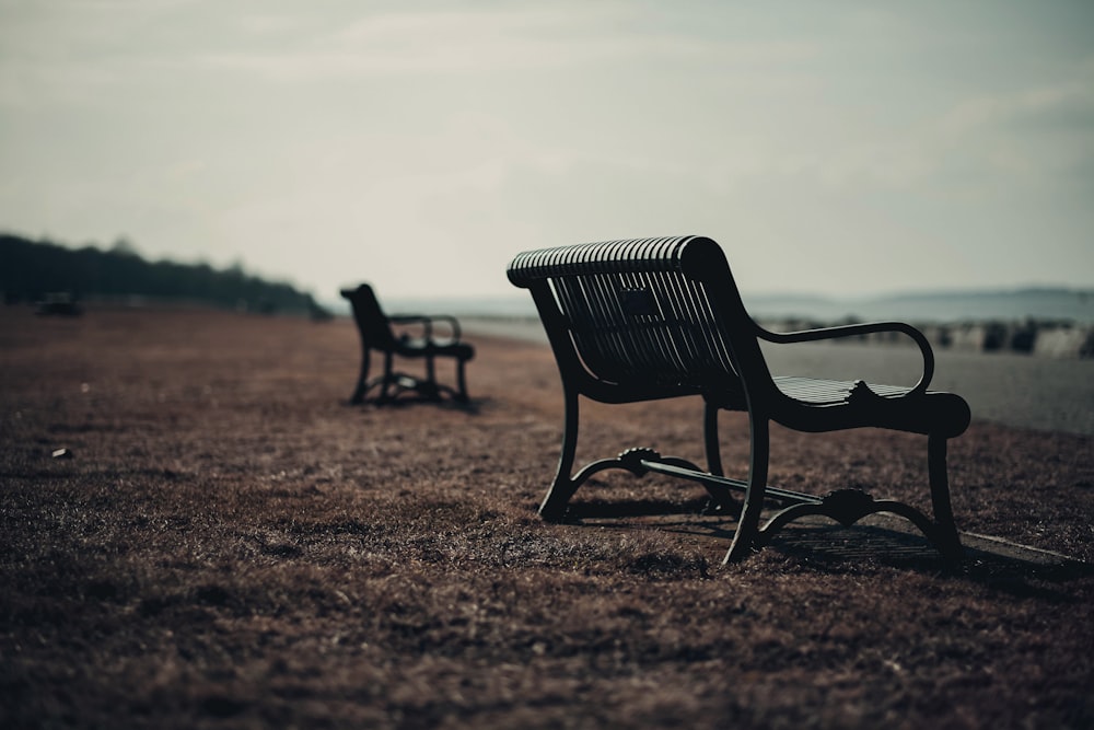 a couple of benches sitting on top of a grass covered field