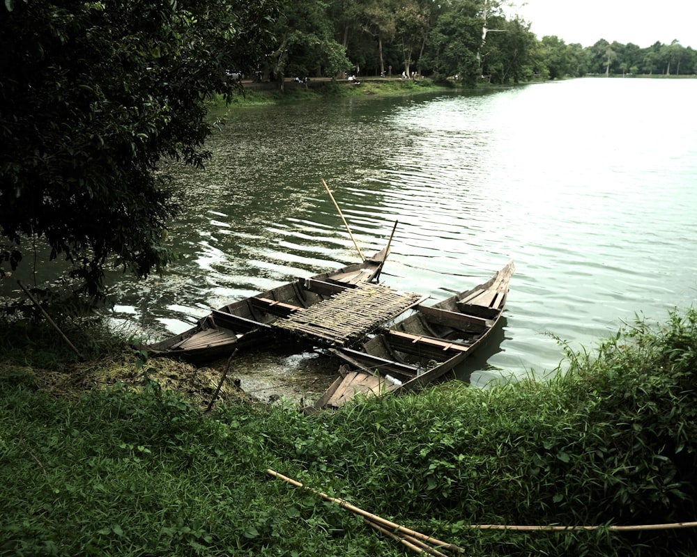 a boat sitting on top of a river next to a lush green field