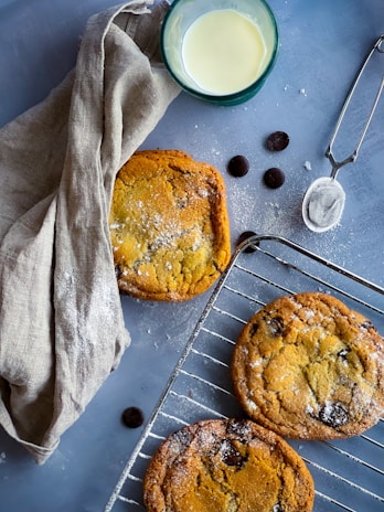 Freshly baked cookies cooling on a wire rack with a glass of milk nearby.
