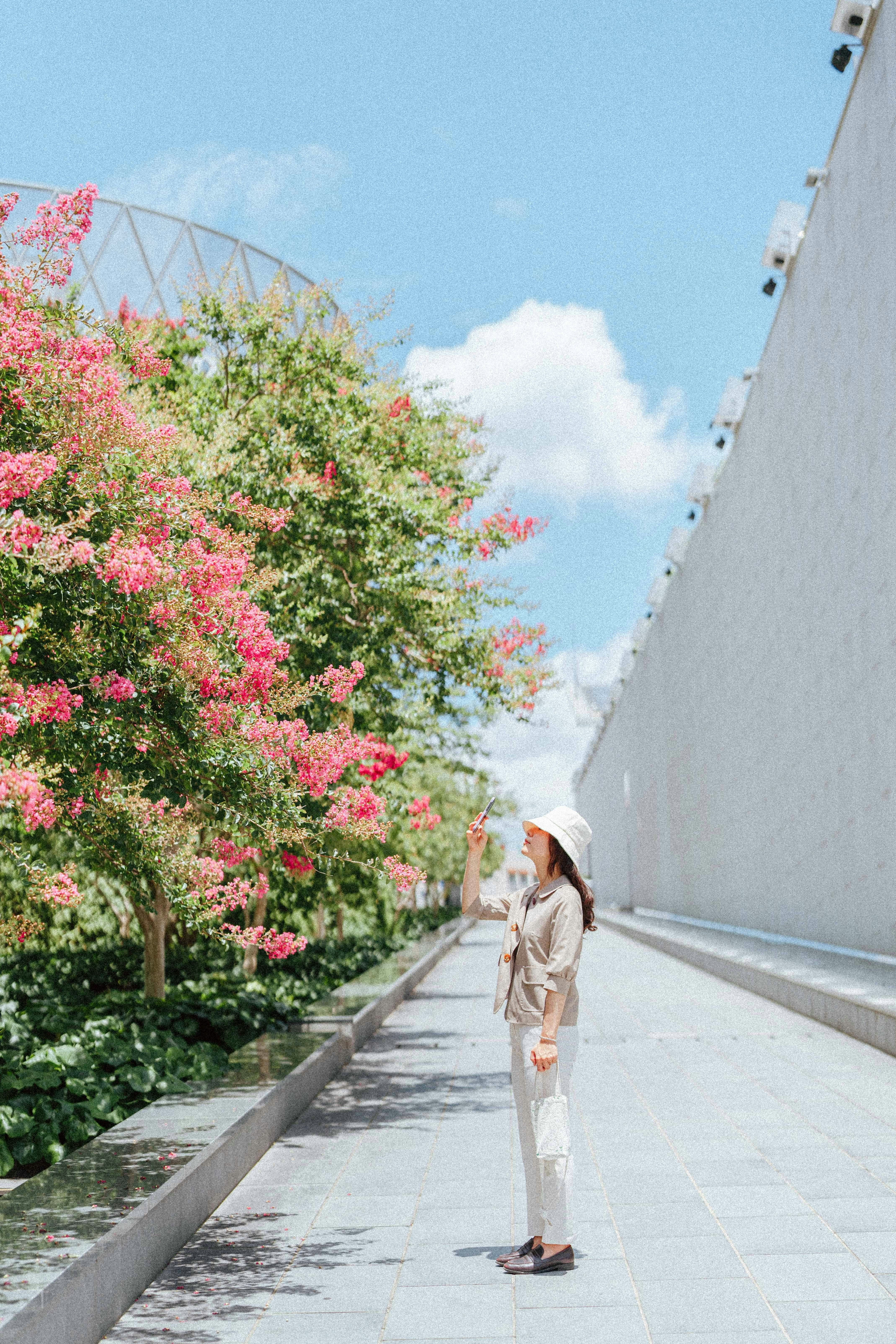 a woman standing on a sidewalk next to flowers
