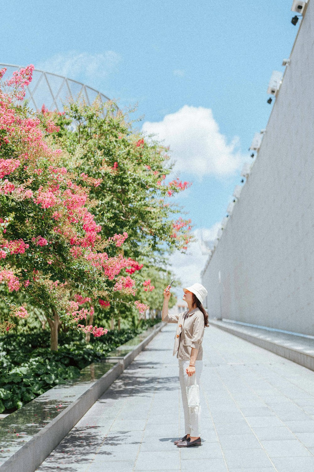 a woman standing on a sidewalk next to flowers