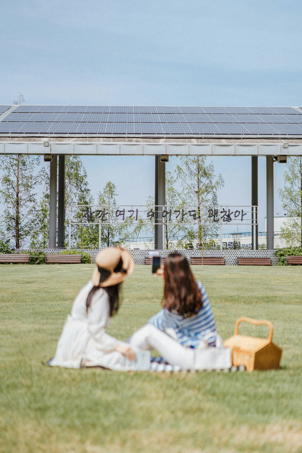 two women sitting on the grass in front of a building