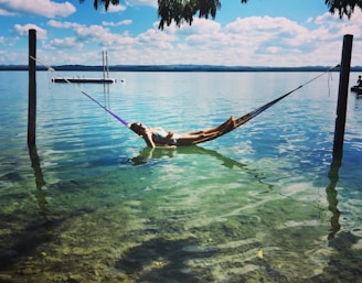 a person laying in a hammock in the water
