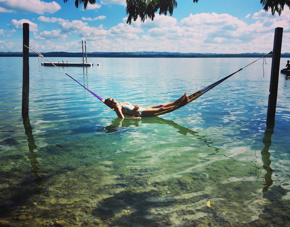 a person laying in a hammock in the water