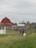 Happy couple inspecting their gated farm plot with open fields and a clear blue sky.
