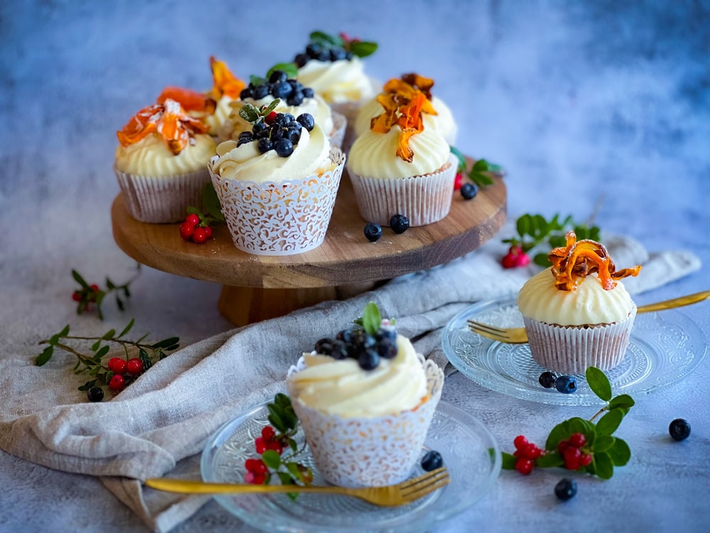 um prato de cupcakes com cobertura e frutas vermelhas