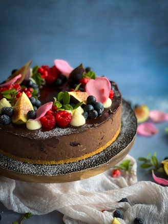 A beautifully decorated chocolate cake topped with fresh berries and edible flowers.