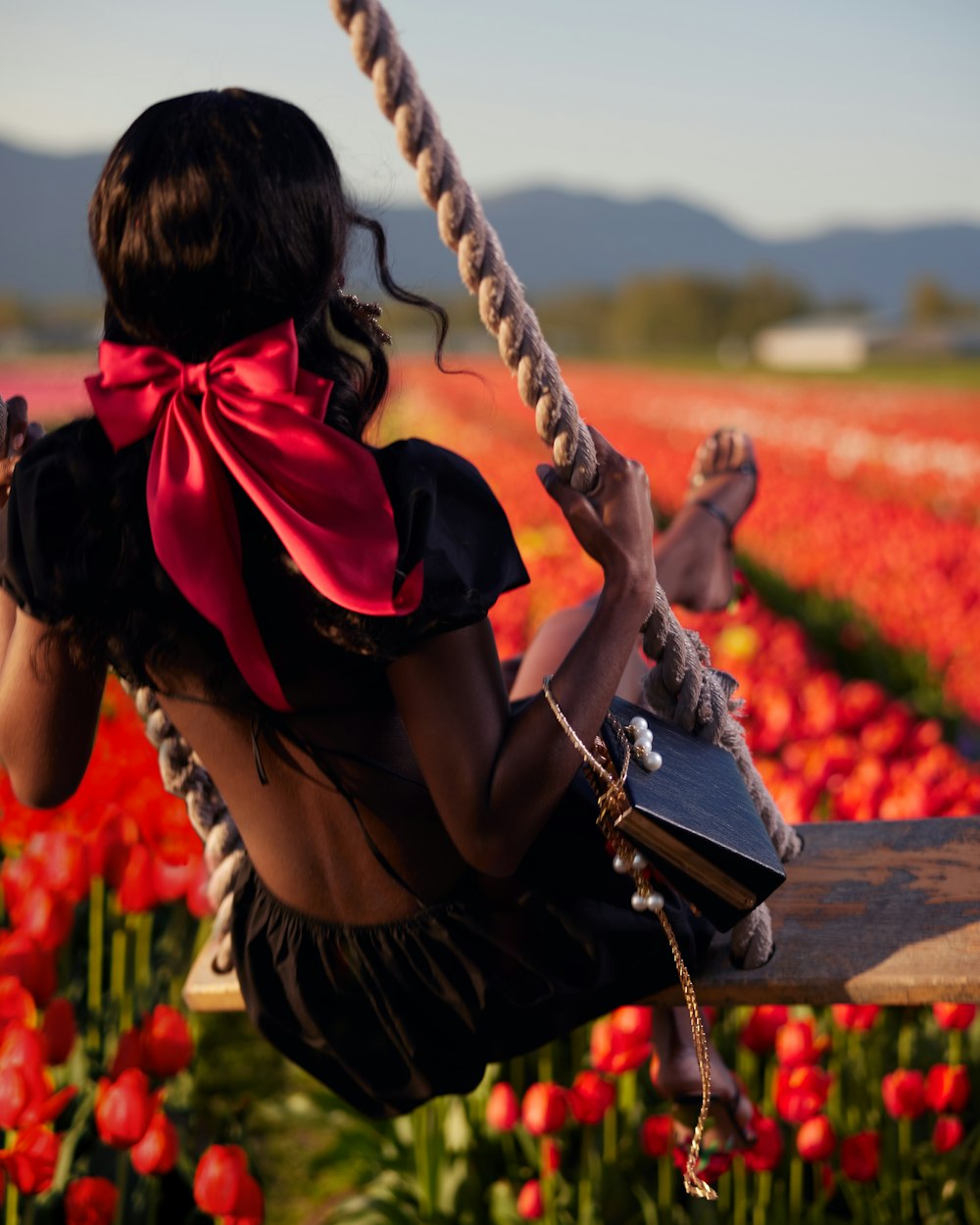 a woman sitting on a swing in a field of flowers
