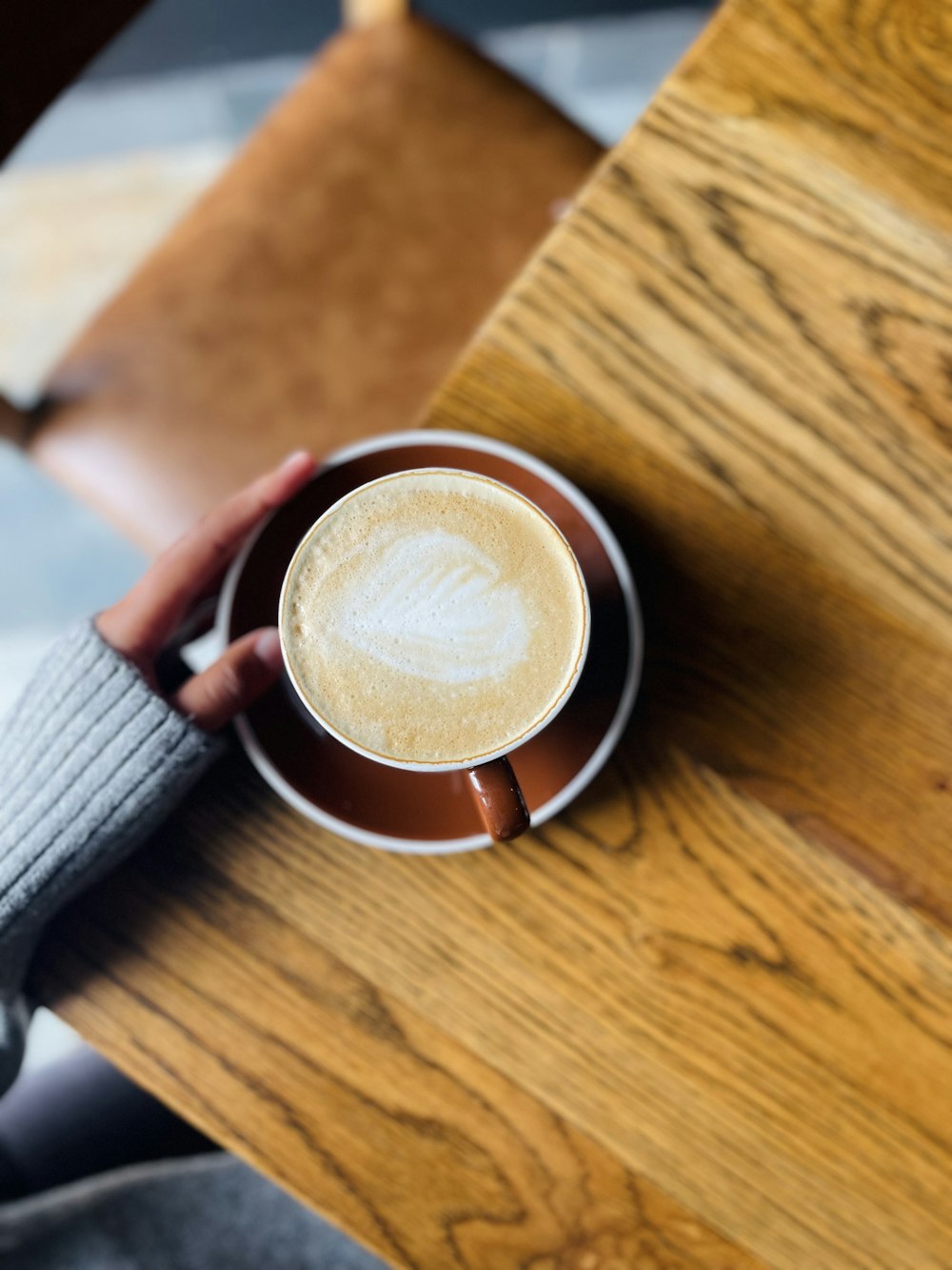 una persona che tiene una tazza di caffè sopra un tavolo di legno