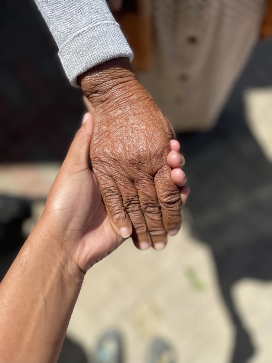 Caregiver holding the hands of an elderly person — a warm, comforting moment
