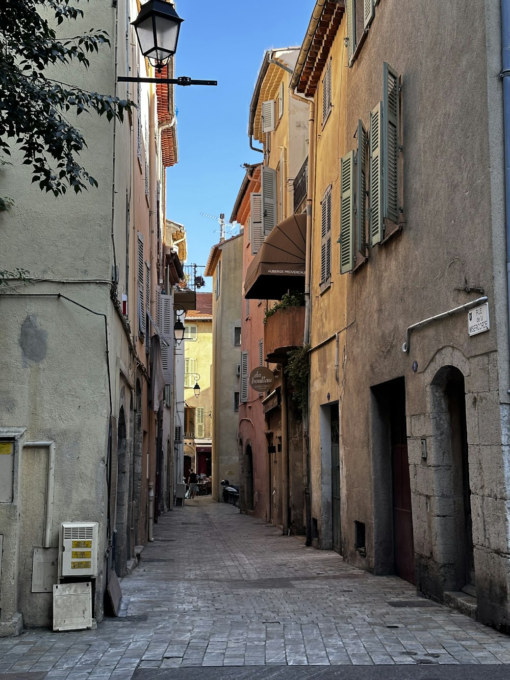 a narrow city street with a lamp post in the middle