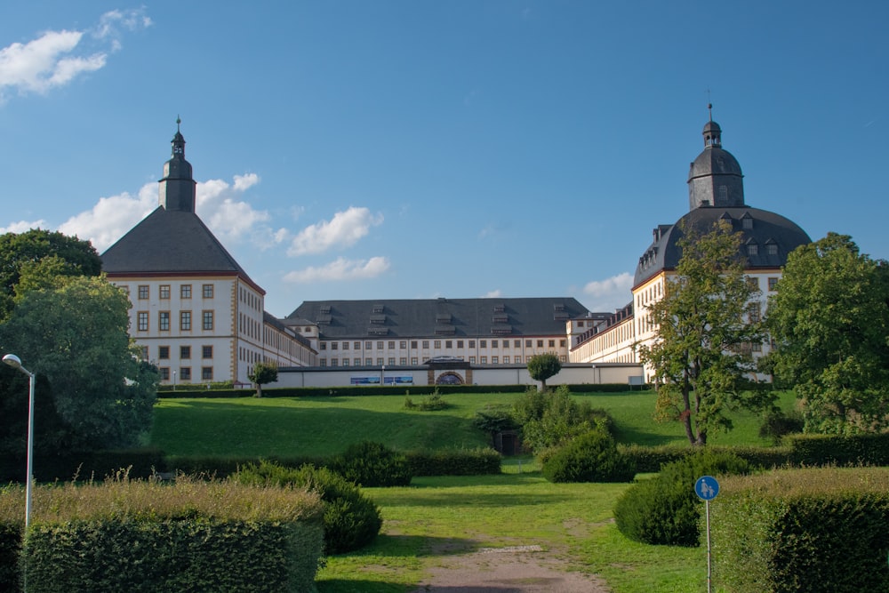 a large white building surrounded by a lush green park