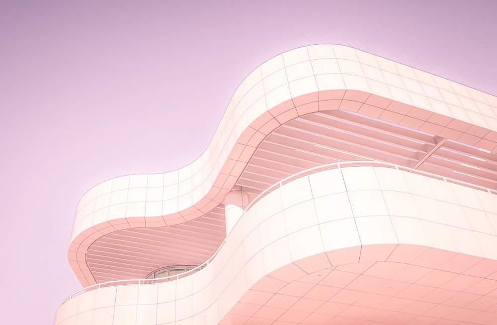 a pink building with a curved bench on the side of it