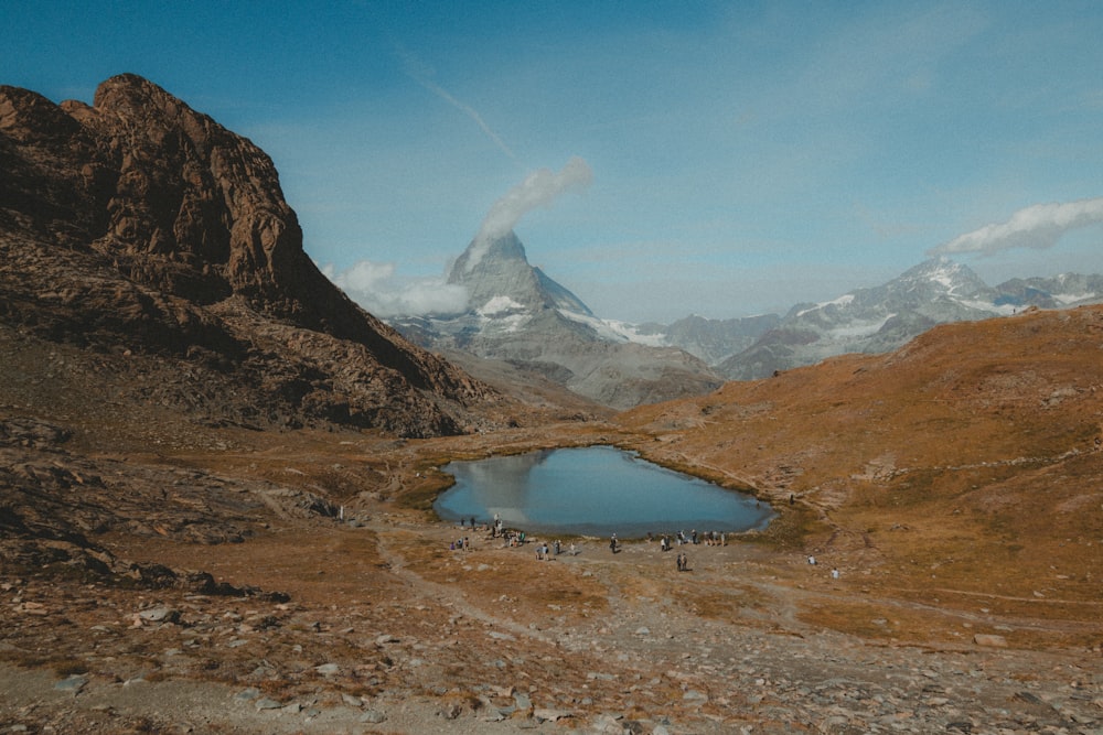 a group of people standing on top of a mountain next to a lake