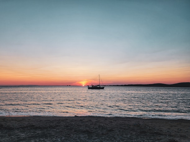 A peaceful sunset over the ocean with a yacht gently rocking in the waves.