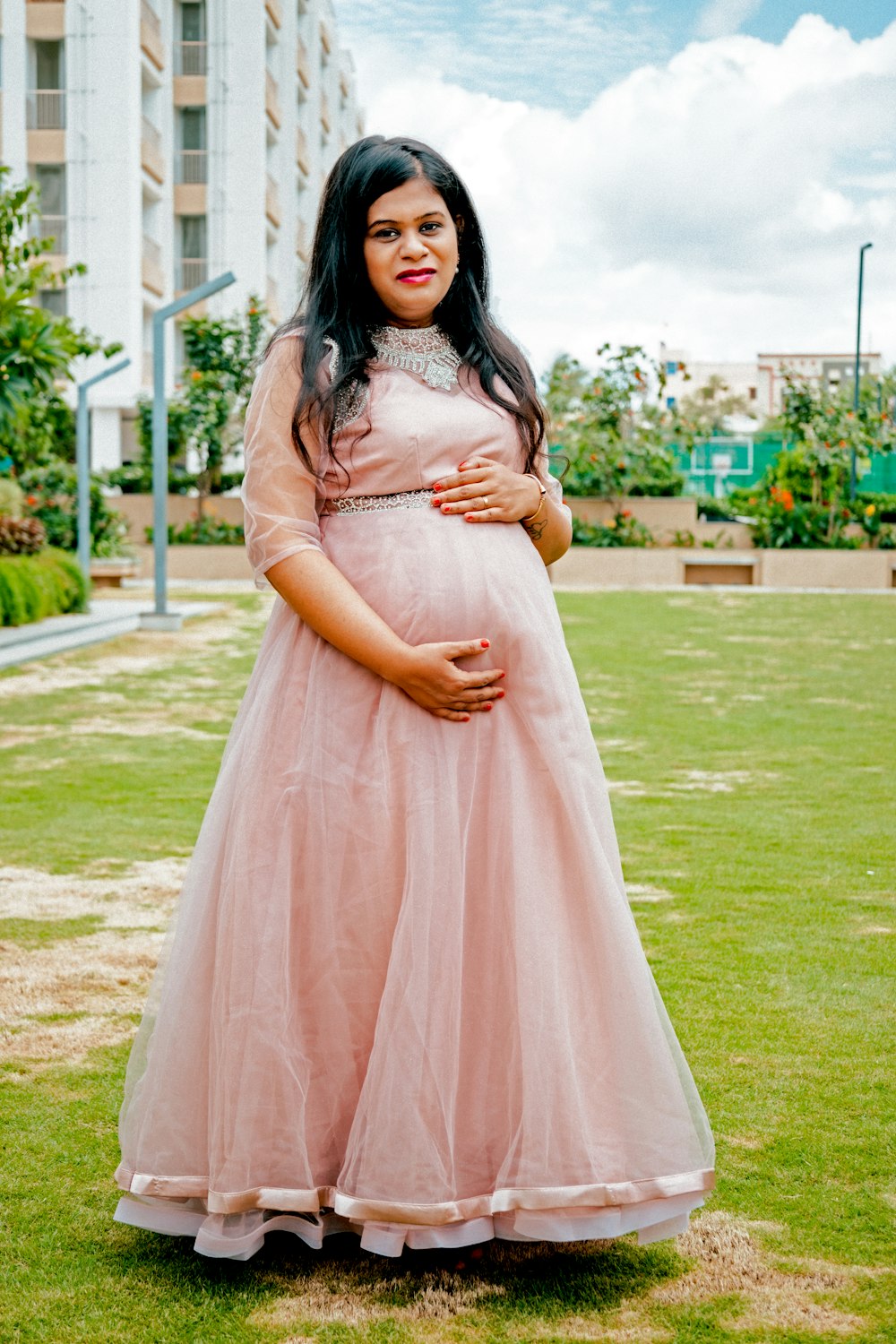 a pregnant woman in a pink dress poses for a picture
