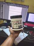 A sleek container of creatine powder with a measuring spoon, set against a clean white background.