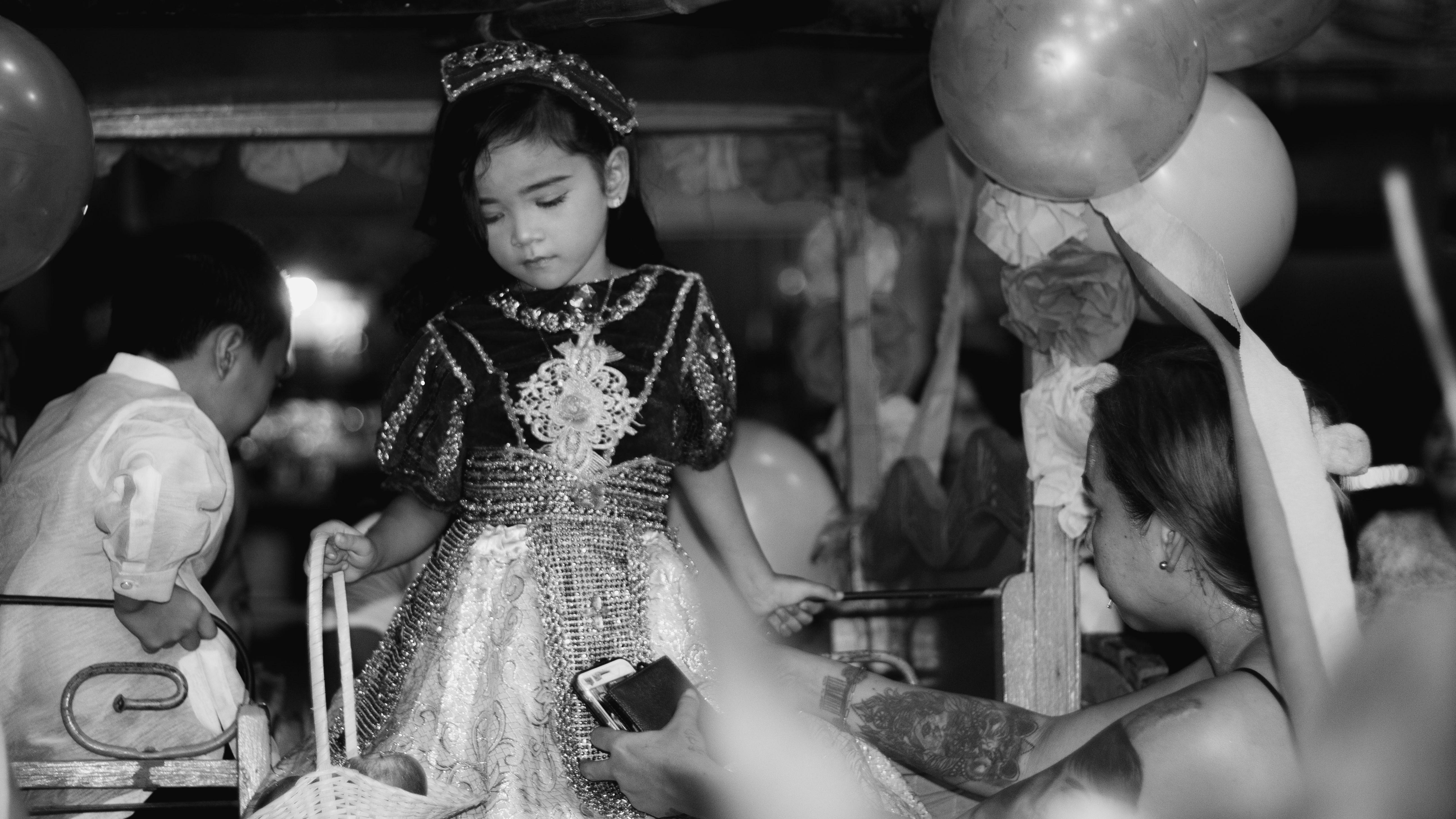 a little girl in a dress standing in front of balloons
