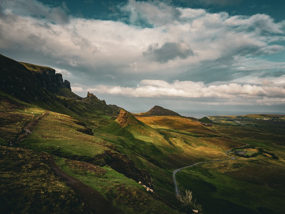 a scenic view of a mountain range with a winding road in the foreground