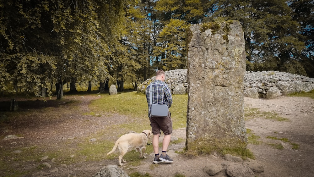 a man standing next to a tall stone pillar