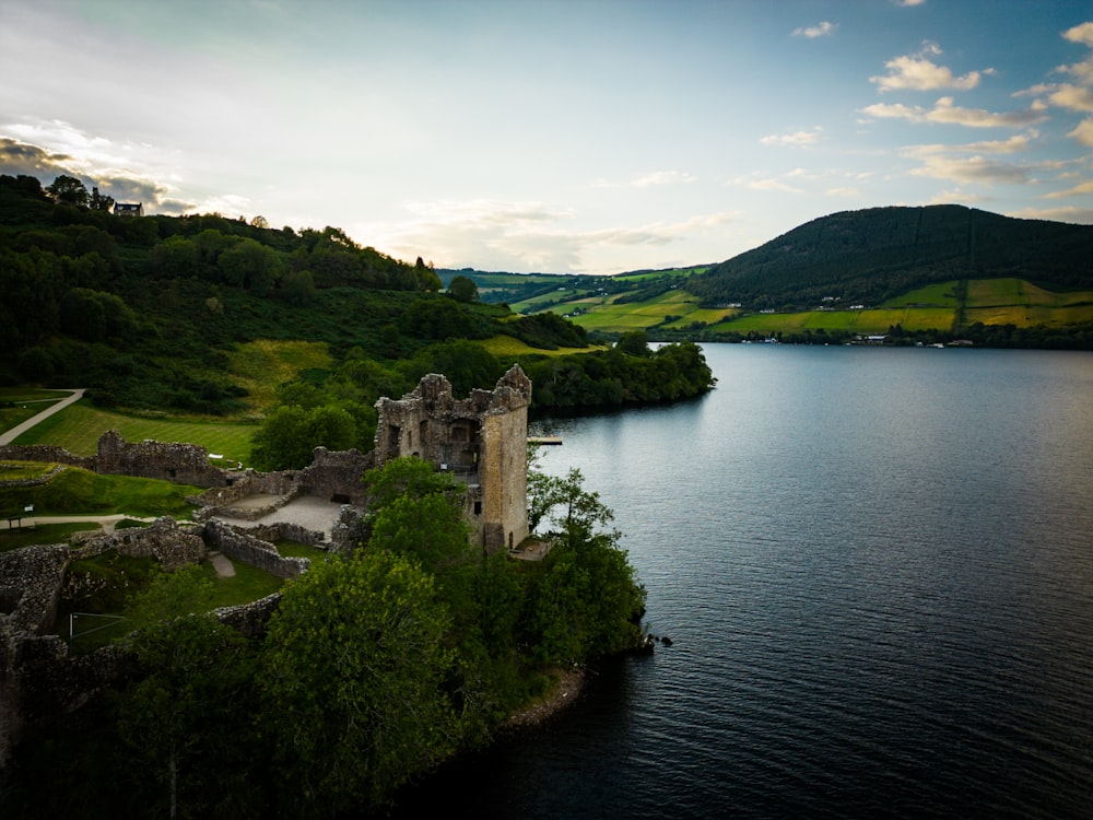 a castle sitting on top of a lush green hillside next to a lake