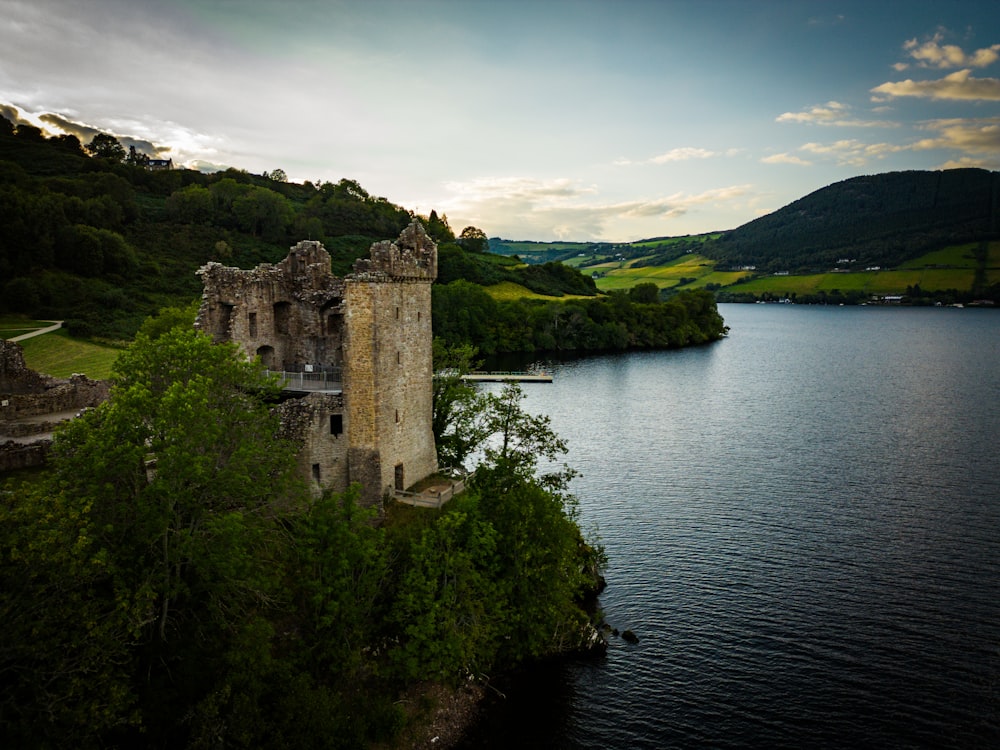 a castle sitting on top of a lush green hillside next to a lake