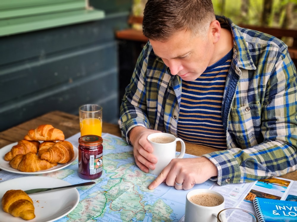 a man sitting at a table with a plate of food and a cup of coffee