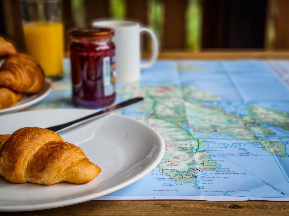 a plate of croissants on a map with a glass of orange juice