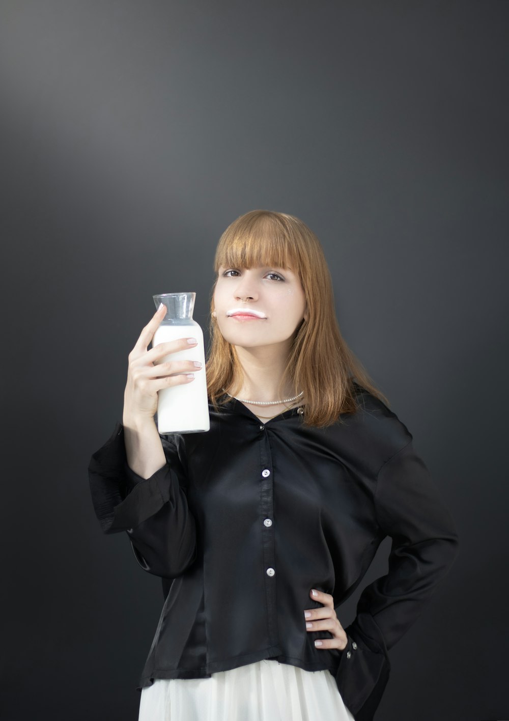 a woman holding a glass and a bottle of milk