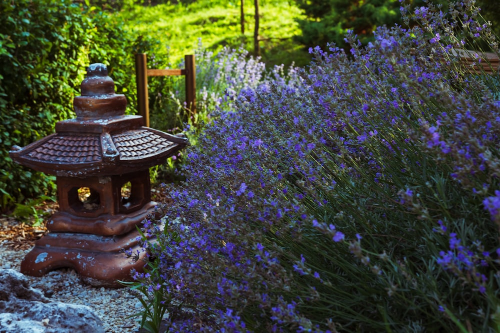 a garden with purple flowers and a wooden lantern