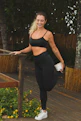 A smiling woman stretching outdoors after a workout session.