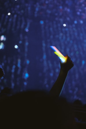 Close-up of hands clapping and waving glow sticks in a dark club atmosphere
