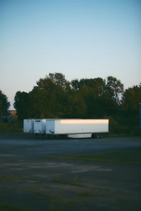 A sleek mobile surveillance trailer parked at a construction site during sunset, cameras actively monitoring.