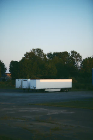 A sleek mobile surveillance trailer parked at a busy construction site during sunset.